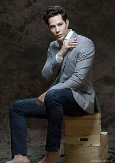 a man sitting on top of a wooden box wearing a suit and holding a cell phone