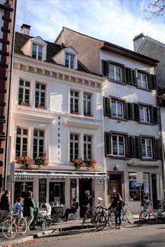 several people are riding their bikes in front of a building with flower boxes on the windows