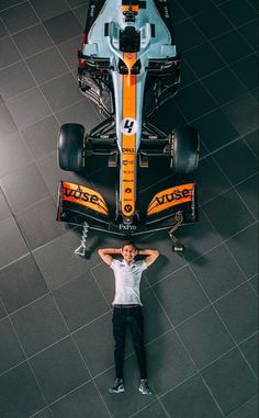 a man standing next to a racing car on top of a tiled floored area
