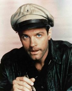 a man wearing a hat and leather jacket