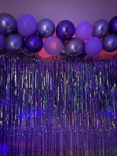 balloons and streamers are hanging from the ceiling in front of a purple wall with blue lights