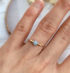 a woman's hand wearing a gold ring with a blue stone on the middle