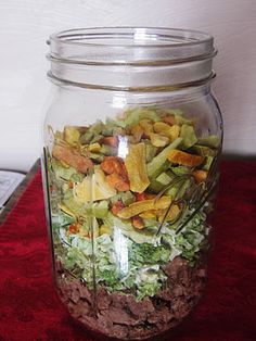 a glass jar filled with food sitting on top of a red table next to a white wall