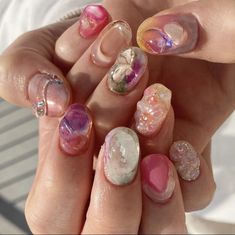 a woman's hands with different colored nail polishes and designs on their nails