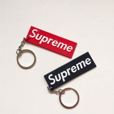 two keychains with the words supreme on them are laying next to each other