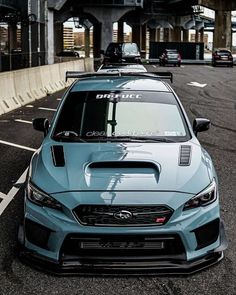 a subarun car is parked on the street in front of an overpass