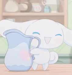 a white bunny holding a blue pitcher on top of a table