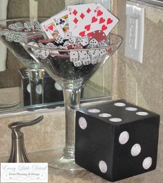 a glass bowl filled with dice and playing cards sitting on top of a counter next to a mirror