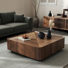 a living room with a couch, coffee table and vases on the floor in front of it