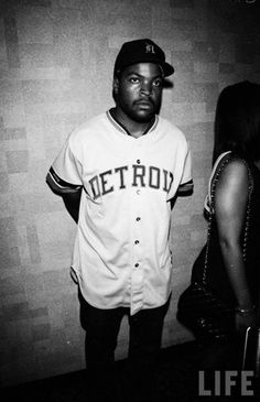 a black and white photo of a man in a baseball uniform standing next to a woman