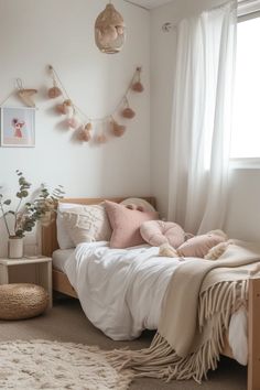 a bedroom with white walls and pink pillows on the bedspread, along with hanging plants