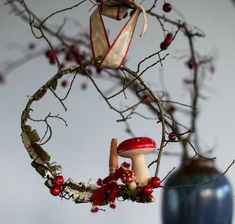 an ornament hanging from a tree with red berries and mushrooms on it's branches