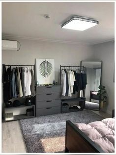 a bedroom with a bed, dressers and clothes hanging on the racks in it