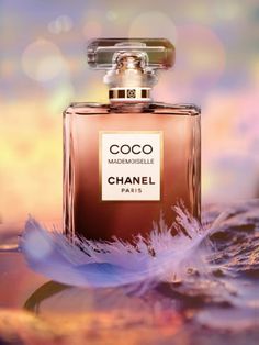 a bottle of chanel coco mademoiselle on a colorful background with feathers