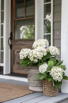 two vases with white flowers on the front porch