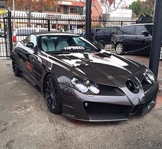 a black sports car parked in front of a fence