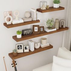 three wooden shelves with various items on them in the corner of a white living room