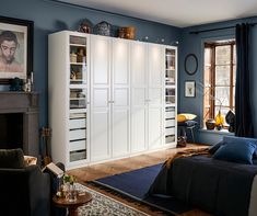 a bedroom with blue walls and white cabinets in it's center area, along with a fireplace