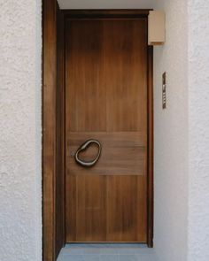 a wooden door with a metal handle on the side of it in front of a white wall