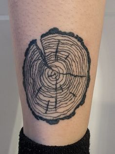 a close up of a person's leg with a tree ring tattoo on it