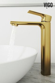 a gold faucet with water running from it's spout in front of a white bowl