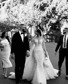 black and white photo of bride and groom walking with their friends in the park on wedding day