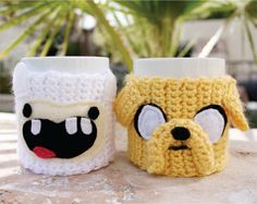 two crocheted cups with faces on them