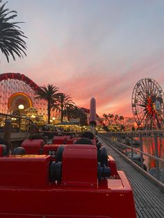 an amusement park at sunset with ferris wheel and palm trees