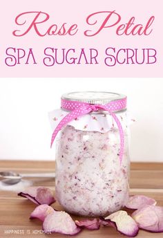 rose petal spa sugar scrub in a glass jar with pink flowers on the side