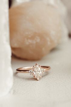 a diamond ring sitting on top of a white surface next to a rock and stone