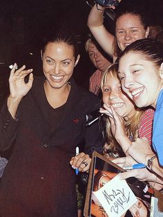 two women are posing for the camera while others hold their cell phones up in the air