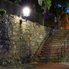 a stone wall with steps leading up to it and a street light on the side