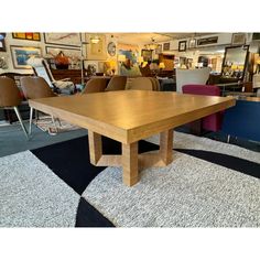 a wooden table sitting on top of a carpeted floor next to chairs and tables