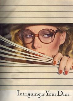 a woman wearing glasses peeking out from behind bars with the words, intriguing is your dior