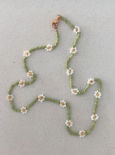a beaded necklace with white and yellow flowers hanging from it's side on a table
