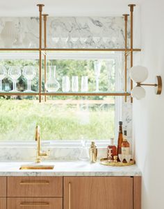 a kitchen with marble counter tops and wooden cabinets in front of a window filled with wine glasses