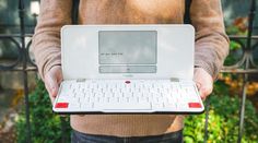 a man holding a laptop computer in his hands with a keyboard on the back of it