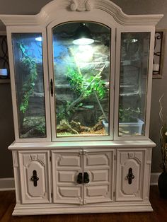 an aquarium is in the corner of a white hutch with drawers and cupboards