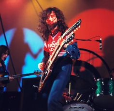 a man with long hair playing an electric guitar