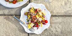 two plates with salad on them sitting on the ground next to each other, one has a fork in it