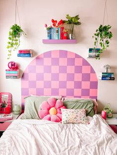 a bed with pink and purple headboard in a bedroom next to bookshelves