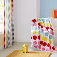 a child's bedroom with blue walls and white flooring, colorful polka dot throw blanket