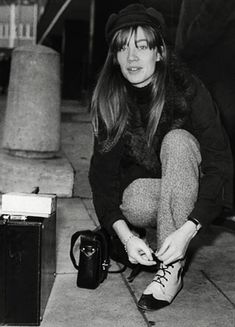 a black and white photo of a woman kneeling down with her shoes on the ground