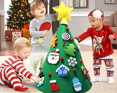 three children are playing around a christmas tree