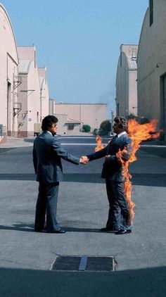 two people shaking hands with fire in the middle of an empty parking lot next to buildings