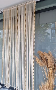 the window is decorated with gold beading and some dried grass in front of it
