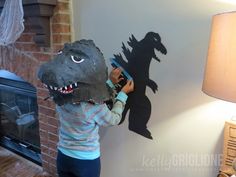 a child is painting a dinosaur on the wall with a stencil and a lamp