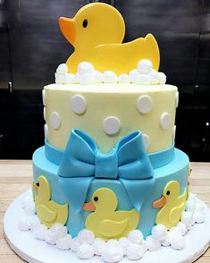 a three tiered cake decorated with rubber ducks and bow ties on a wooden table