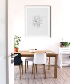 a dining room table with two chairs and a framed art piece on the wall above it