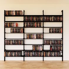 there is a large book shelf with many books and dvds on it in front of a white wall